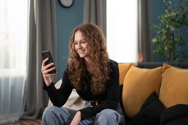 Portrait of young beautiful casual student woman holding smartphone looking at screen using app