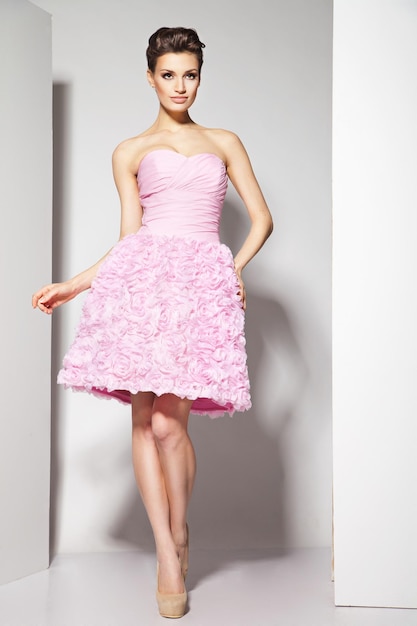 Portrait of young beautiful caucasian brunette in gorgeous dress on white background