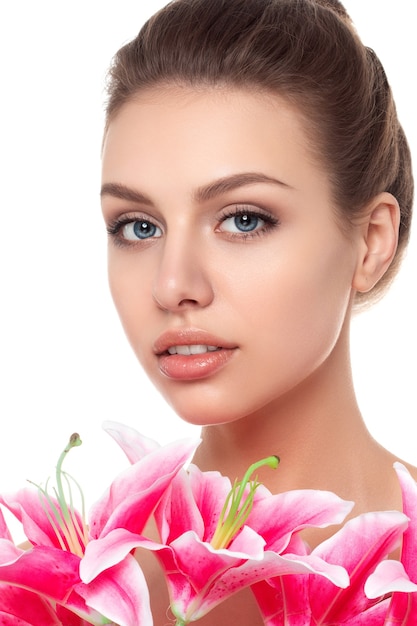 Portrait of young beautiful caucasian woman with pink lilies isolated over white background