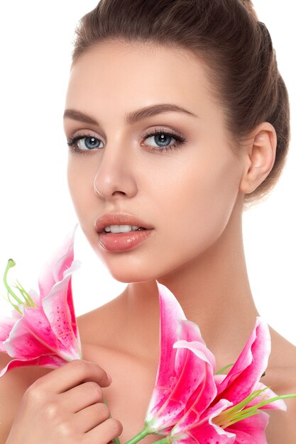 Portrait of young beautiful caucasian woman with pink lilies isolated over white background