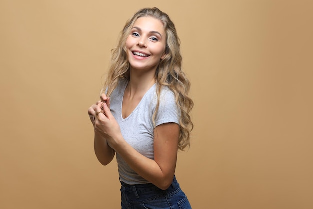 Portrait of young beautiful cheerful girl smiling looking at camera over beige background.