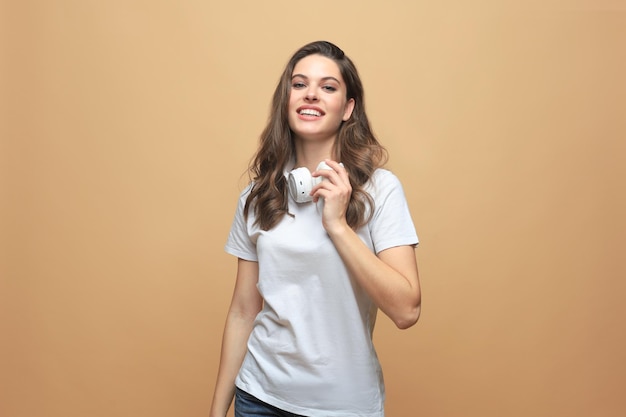 Portrait of young beautiful cheerful girl smiling looking at camera over beige background.