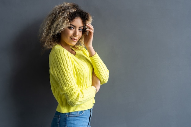 Portrait of young beautiful cute cheerful black girl smiling looking at camera over gray background.