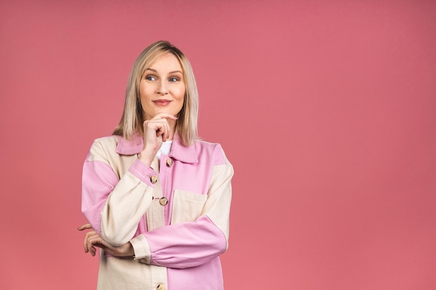 Portrait of a young beautiful cute cheerful blonde woman smiling looking at the camera isolated over pink background.