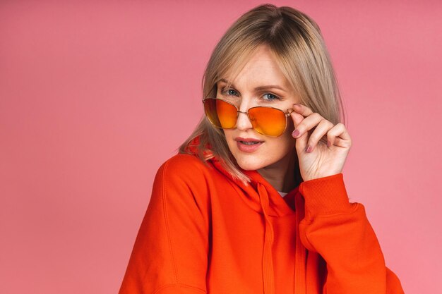 Portrait of a young beautiful cute thinking serious blonde woman isolated over pink background.