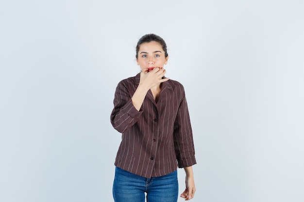 Portrait of young beautiful female trying to whistle with fingers in jacket and looking blissful front view