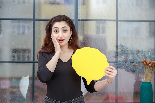 Portrait of young beautiful girl holding idea bubble and and put her hand to her face