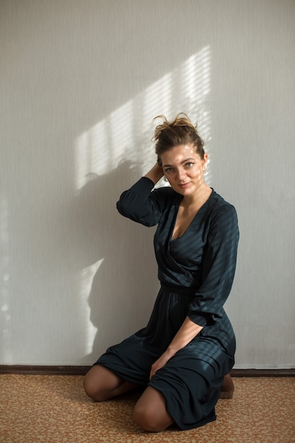 Portrait of a young beautiful girl in a room on a background of a gray wall with shadows