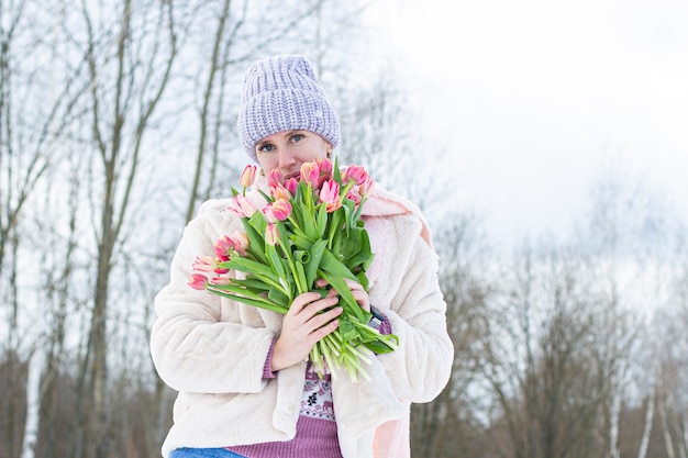 Foto ritratto di una giovane bella ragazza in strada in inverno con i tulipani