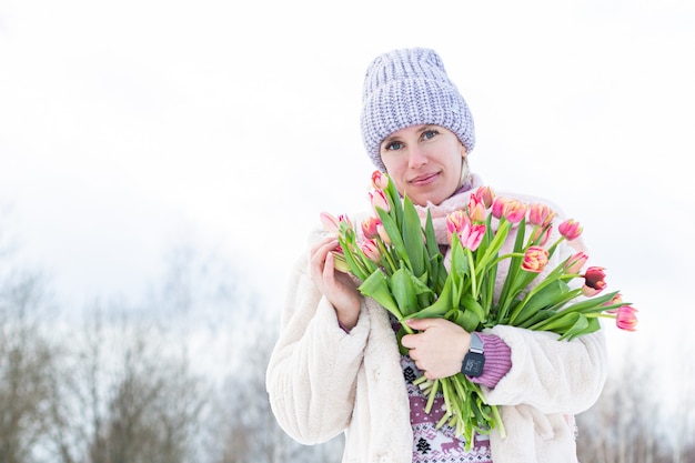 Foto ritratto di una giovane bella ragazza in strada in inverno con i tulipani