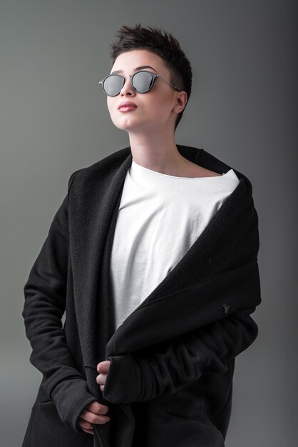 Portrait of a young beautiful girl in sunglasses against a dark background