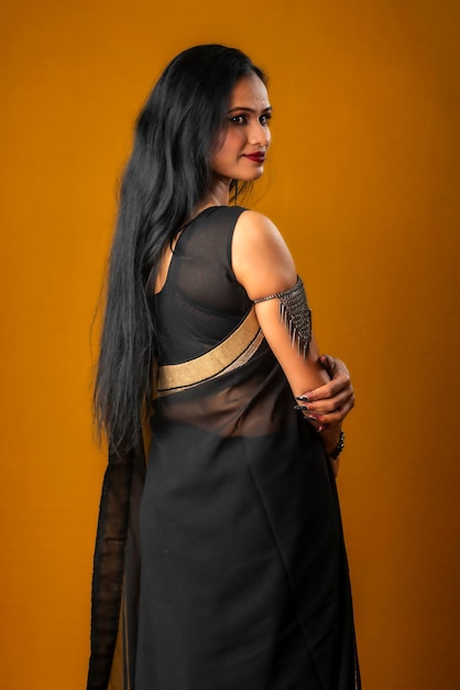 Premium Photo | Portrait of a young beautiful girl wearing traditional black  saree posing on a brown background