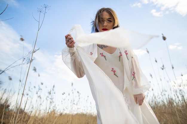 Portrait of young beautiful girl in the white dress in wheat field, walking, carefree. 