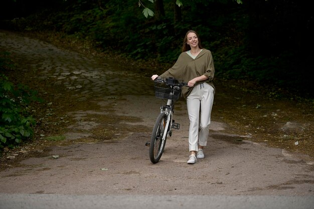 Портрет молодой красивой девушки с велосипедом в парке
