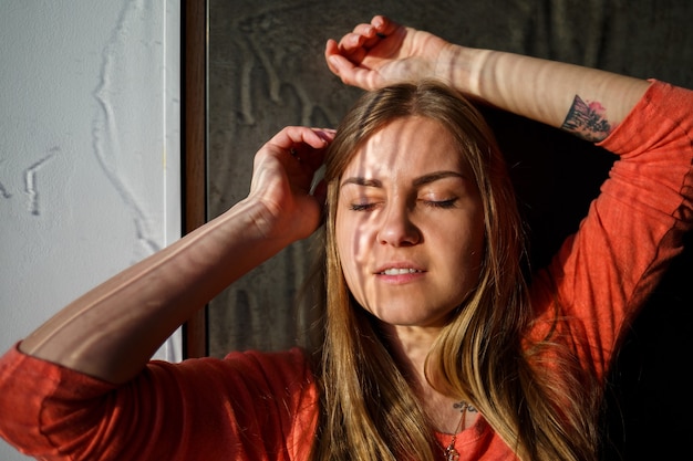 Portrait of a young beautiful girl with light through a wet window. Stains from water and light on the face