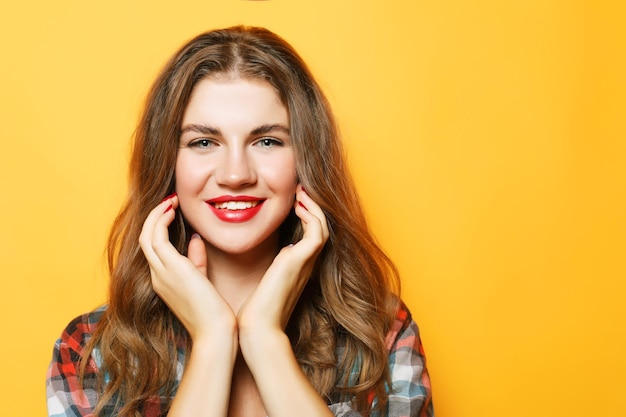 Portrait of a young beautiful girl on a yellow background She smiles and looks happy