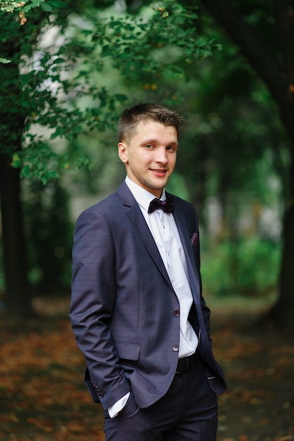 Portrait of a young beautiful groom outdoors on nature.