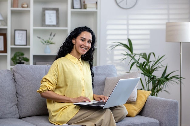 Portrait of young beautiful hispanic woman at home with laptop woman smiling and looking at camera