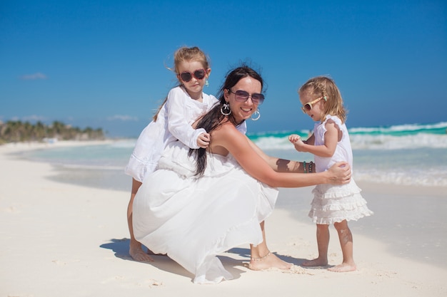 Ritratto di giovane bella madre e le sue adorabili figlie in spiaggia tropicale