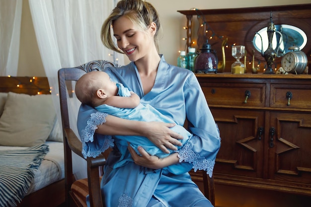파란 천으로 싸인 귀여운 아기를 안고 있는 아름다운 젊은 어머니의 초상화
