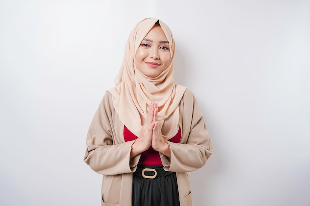 Portrait of a young beautiful Muslim woman wearing a hijab gesturing Eid Mubarak greeting