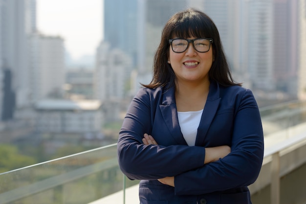 Portrait of young beautiful overweight Asian businesswoman against view of the city