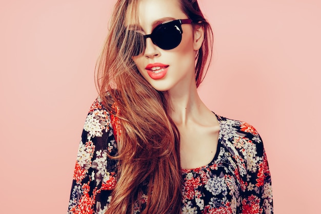 portrait of young beautiful slim woman in sexy dress with sensual lips  wearing sunglasses smiling and posing