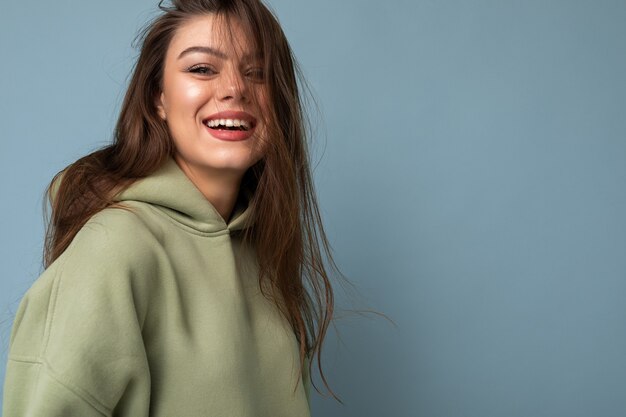 Ritratto di giovane bella ragazza sorridente in felpa con cappuccio verde hipster alla moda