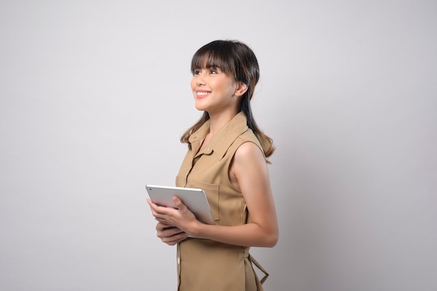 A portrait of young beautiful smiling woman is holding tablet over white background studio