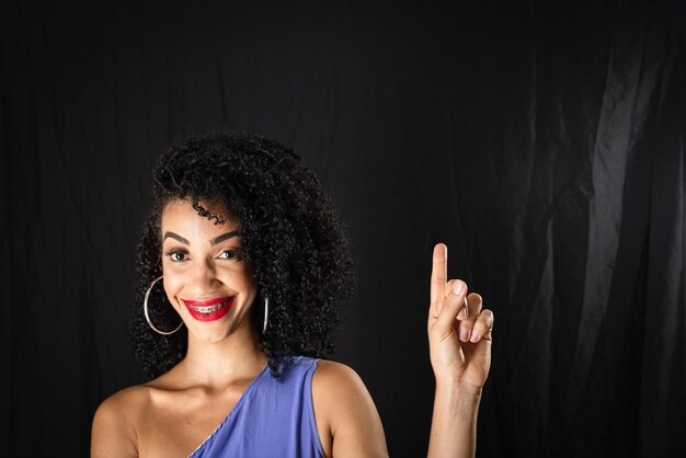 Foto ritratto di una giovane donna bella e sorridente che punta verso l'alto indossando abiti blu