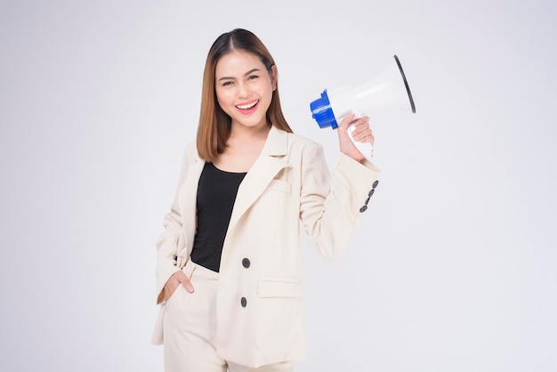 Portrait of young beautiful smiling woman in suit using megaphone to announce