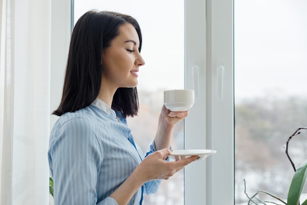 一杯のコーヒーと若い美しい笑顔の女性の肖像画