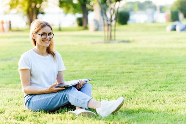 Portrait of young beautiful smiling woman with tablet pc, outdoors