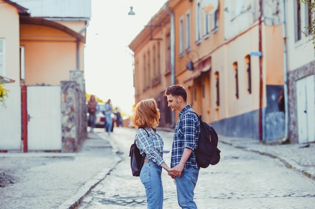 Portrait of young beautiful stylish couple looking at each other standing on the old city street