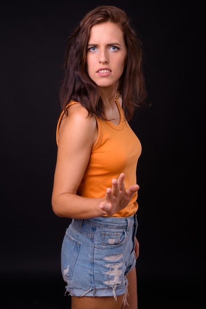 Portrait of young beautiful woman against black wall