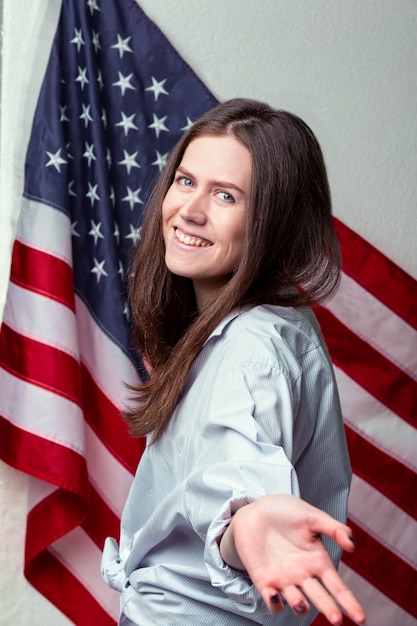 Portrait of a young beautiful woman against the wall of the American flag