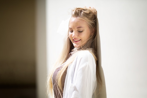 Portrait of young beautiful woman blonde hair standing against wall with copy space