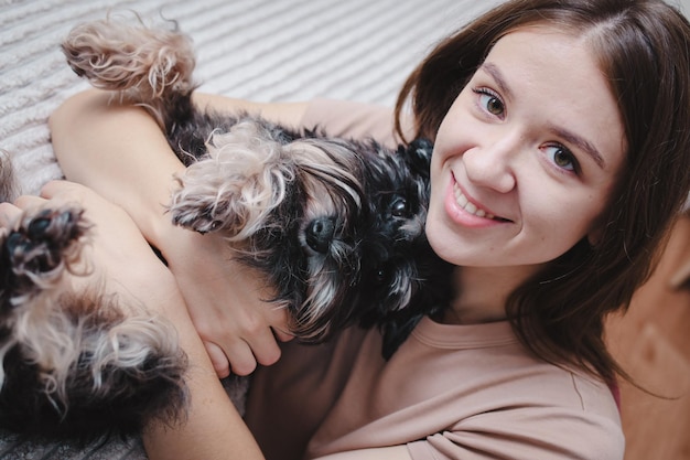 Foto ritratto di una giovane bella donna e del suo piccolo cane nero a casa