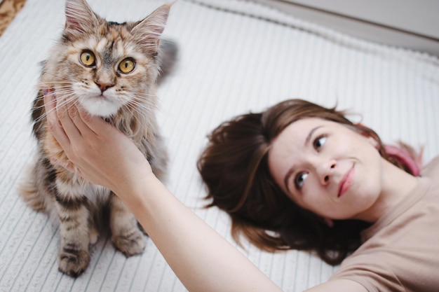 Photo portrait of a young beautiful woman hugging her cat at home