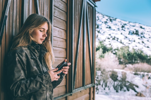 写真 携帯電話を使用して雪の中で冬の肖像若い美しい女性