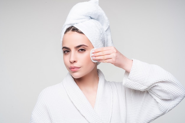 Ritratto di giovane bella donna sta pulendo il viso dal trucco con dischetti di cotone per la cura della pelle ed essere...