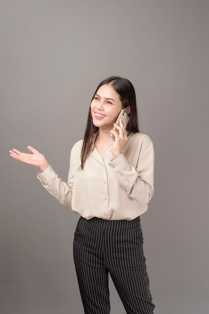 Portrait of young  Beautiful woman is using cellphone on gray background