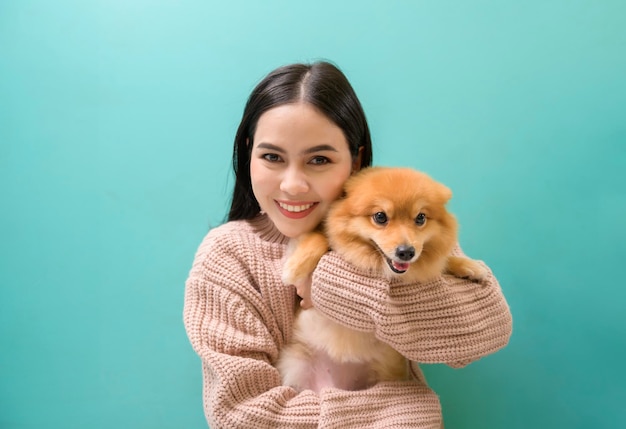Portrait of Young beautiful woman kisses and hugs her dog over green background