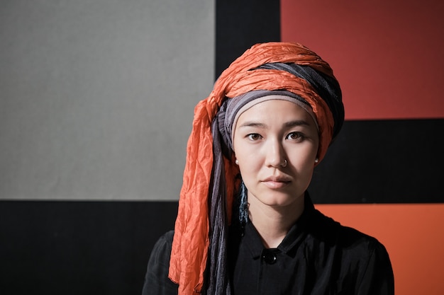 Foto ritratto di giovane bella donna in abiti musulmani che guarda l'obbiettivo contro il muro colorato