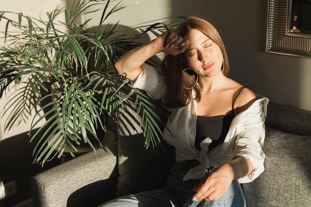 Portrait of young beautiful woman near window with shadow from flowers on her face Morning spring aesthetics