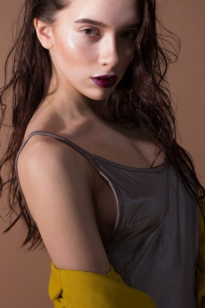 Portrait of a young and beautiful woman posing on the beige.