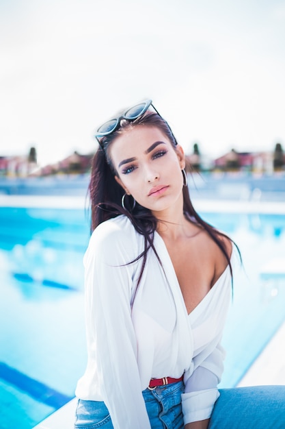 Portrait of young and beautiful woman posing near swimming pool