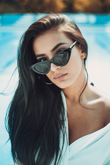 Portrait of young and beautiful woman posing near swimming pool