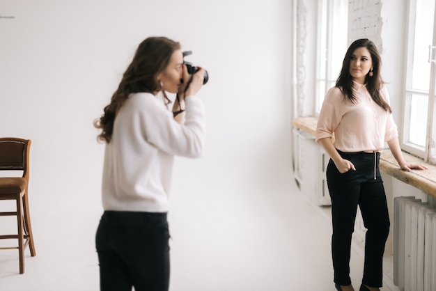 Portrait of young beautiful woman posing in photo studio for female photographer