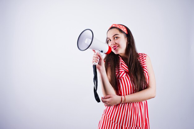 Portrait of a young beautiful woman in red dress talking into megaphone.